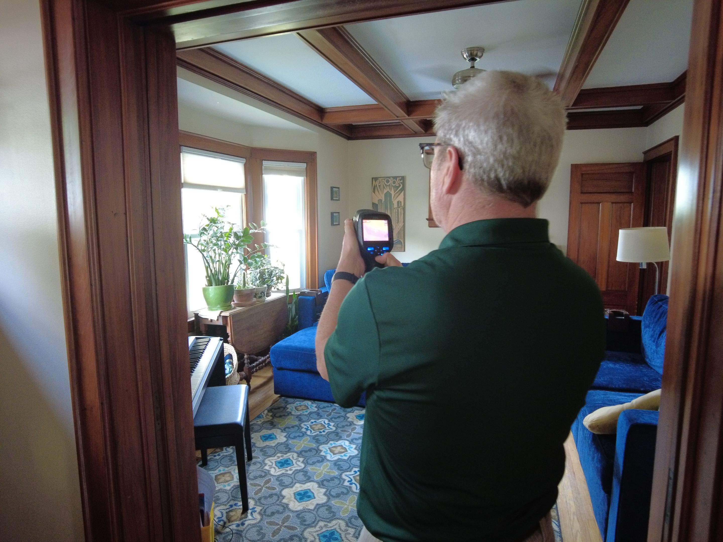 A man with a thermal camera measuring the heat in a room.
